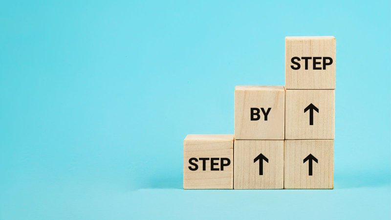 Wooden blocks built up into steps to show continuous improvement is a series of small steps
